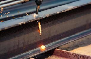 Welder working on metal beam, emitting bright sparks as part of welding process. Skilled labor. Danger of industrial work, and craftsmanship required in metal fabrication. Skilled hands control flame. photo