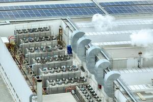 Sustainable industrial rooftop. Aerial view showcasing solar panels, ventilation systems, and industrial chillers. Renewable energy and efficient cooling in modern manufacturing facilities. photo