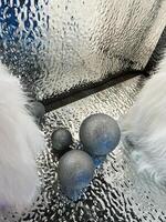 Silver glittering orbs on a textured reflective surface with fluffy white objects photo