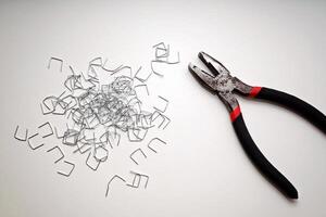Pliers and Staples on White Surface in Minimalist Composition with Copy Space. photo