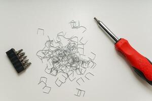 Screwdriver, Bits, and Staples on White Surface in Organized Layout with Copy Space. photo