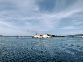 a ferry in the waters near a small island with a blue sky photo