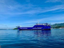 blue ferry boat on the sea with mountains in the background photo