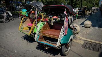Pedicab Parked on Urban Street in Bright Daylight, pedicab or rickshaw or locals calls it becak with a canopy is parked on a sunny street, reflecting a vibrant urban scene photo