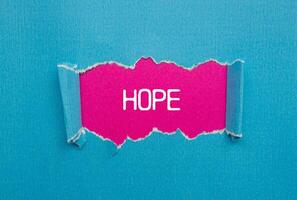 Hope message written on ripped torn blue paper with pink background. Conceptual hope symbol. Copy space. photo
