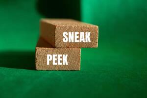 Sneak peek message written on wooden blocks with green background. Conceptual sneak peek symbol. Copy space. photo