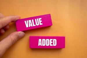 Value added message written on pink wooden blocks with orange background. Conceptual value added symbol. Copy space. photo