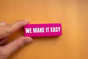 We make it easy message written on pink wooden block with orange background. Conceptual we make it easy symbol. Copy space. photo