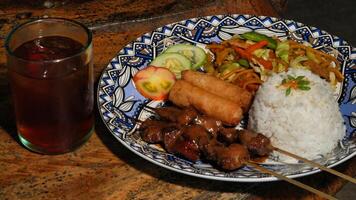 a plate of food with rice and meat on skewers photo