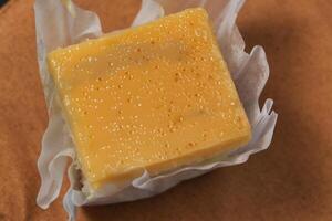 a square of yellow cake sitting on a paper wrapper photo