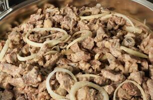 a pan with meat and onions in it photo