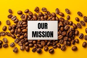 Our mission message written on white paper card on yellow background with coffee beans. Conceptual our mission symbol. photo