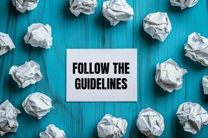 Follow the guidelines message written on white card with crumpled paper balls. Conceptual follow the guidelines symbol. photo