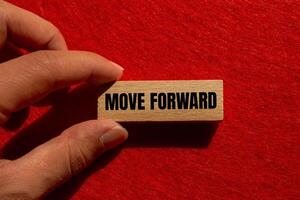 Move forward message written on wooden block with red background. Conceptual move forward symbol. Copy space. photo