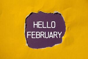 Hello february message written on ripped torn yellow paper with purple background. Conceptual hello february symbol. Copy space. photo