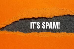 It's spam message written on ripped torn orange paper with gray background. Conceptual it's spam symbol. Copy space. photo