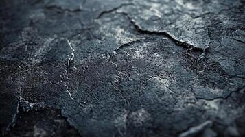 Close up of a cracked and worn surface. The surface is dark and has a rough texture photo