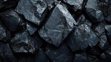 Close up of a pile of rocks with a dark color. The rocks are piled up in a way that they form a square shape. The image has a moody and mysterious feel to it photo