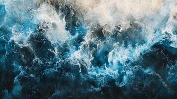 The image is of a large wave crashing into the ocean. The water is a deep blue color, and the sky is a light blue color. Scene is one of power and energy, as the wave is crashing down with force photo