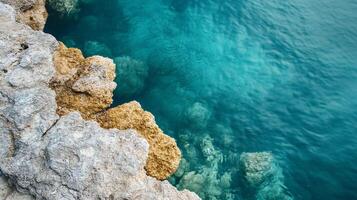 Rocky shoreline with a body of water in the background. The water is clear and calm, and the rocks are jagged and rough. The scene is peaceful and serene, with the water reflecting the sky photo