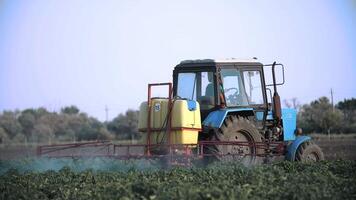 Pesticide Sprayer Tractor working on a large green field. following on the side a tractor spraying wheat field against diseases. Farmer spraying vegetable fields. video