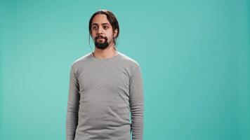Portrait of serious Arab man standing isolated against blue studio background. Confident person having focused expression, suggesting determination and assertiveness, studio backdrop video