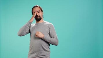 Man feeling exhausted from overworking and lack of sleep, rubbing eyes and yawning, isolated over studio background. Tired person feeling sleepy, being fatigued, studio backdrop, camera B video