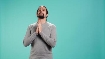 Pious man praying to his god, asking for forgiveness. Spiritual person doing worship hand gesturing, confessing, begging for pardon, isolated over studio background, camera B video