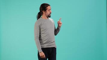 Salesman pointing around with finger, doing recommendation, talking with audience. Man showing copy text space, doing advertisement, isolated over studio background, camera A video