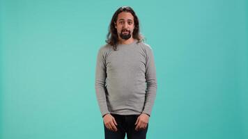 Portrait of spiteful man making exaggerated silly faces, mimicking someone, doing mocking gesturing. Person making goofy facial expressions, being playful, making fun, studio background, camera A video