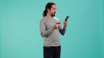 Man adding payment method on website, isolated over blue studio background. Cheerful person excited to do online shopping, carefully typing credit card information, camera A video