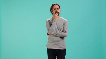 Pensive man deep in thoughts, doing ruminating hand gesturing, isolated over studio background. Unsure person doing stroking chin gesture, thinking, studio backdrop, camera A video