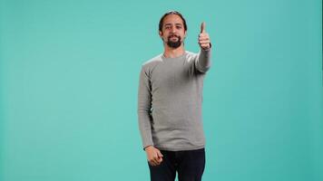 Portrait of upbeat man showing thumbs up sign gesturing, exulting happy facial expression and satisfaction. Jolly Arab person being excited, doing approving hand gesture, studio background, camera A video