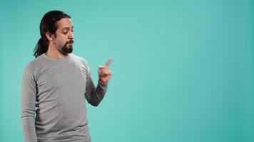 Salesman pointing around with finger, doing recommendation, talking with audience. Man showing copy text space, doing advertisement, isolated over studio background, camera B video