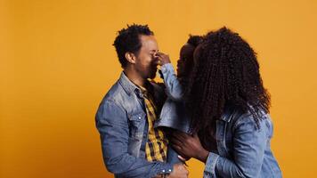 Portrait of african american family with a small boy posing in studio, showing affection and love towards each other and feeling happy. Grateful husband and wife holding their toddler. Camera B. video