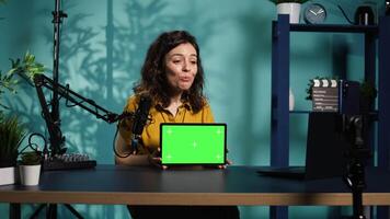 Happy internet star being sponsored by partnering brand to do mockup tablet unboxing content. Smiling tech specialist does influencer marketing, presenting green screen device, camera B video