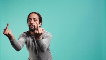 Irked man fighting with friend, doing middle finger sign gesturing, isolated over studio background. Outraged person arguing during conversation, doing obscene hand gestures, camera B video