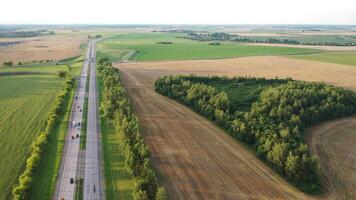 Top view of the road with cars and fields around the road.Fields and trees near the highway with moving cars.Belarus video