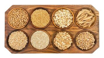 Various types of grains in wooden bowls on a wooden tray photo
