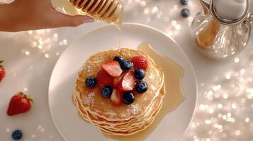A person is pouring syrup over a stack of pancakes photo