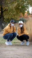 Two girls wearing face masks in a park photo