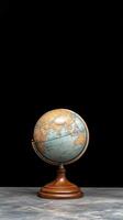 A small globe on a wooden stand in front of a black background photo