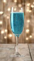 A glass of blue liquid sitting on a wooden table photo