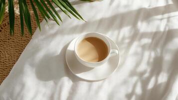 A cup of coffee on a bed with a palm tree photo