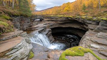 A waterfall is flowing into a cave in the woods photo