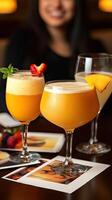 A woman sitting at a table with three glasses of drinks photo