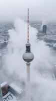 The berlin television tower is seen in the clouds photo