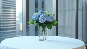 A vase of blue flowers on a table in front of a window photo
