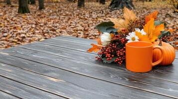 A coffee mug and orange pumpkin on a table in the woods photo