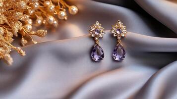 Purple and gold earrings on a silk fabric photo